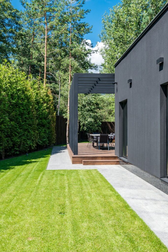 Stylish modern house exterior with a lush green yard and outdoor seating area.