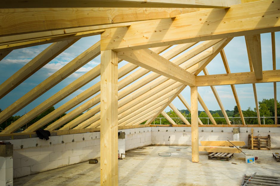Unfinished construction site with a focus on wooden roof trusses under a clear sky.
